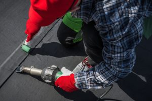 Caucasian Roofing Worker in His 40s. Hot Air Blower Using For EPDM Roof Membrane Rubber Installation